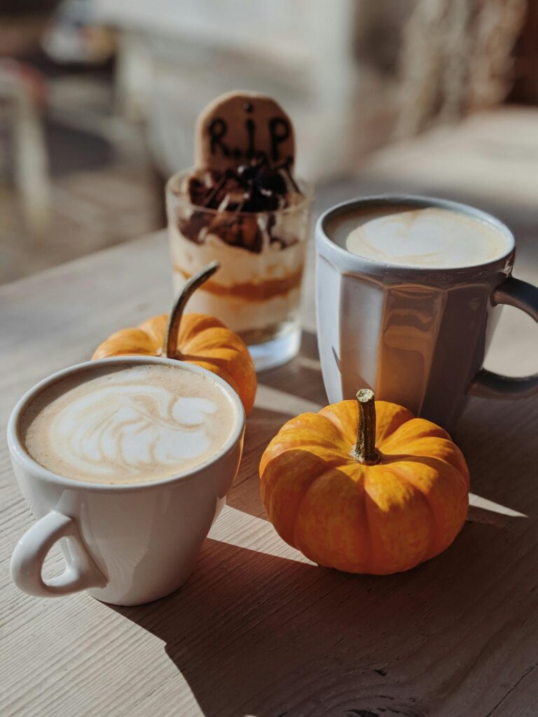Warm autumn coffee scene with pumpkins and Halloween dessert on a rustic table.